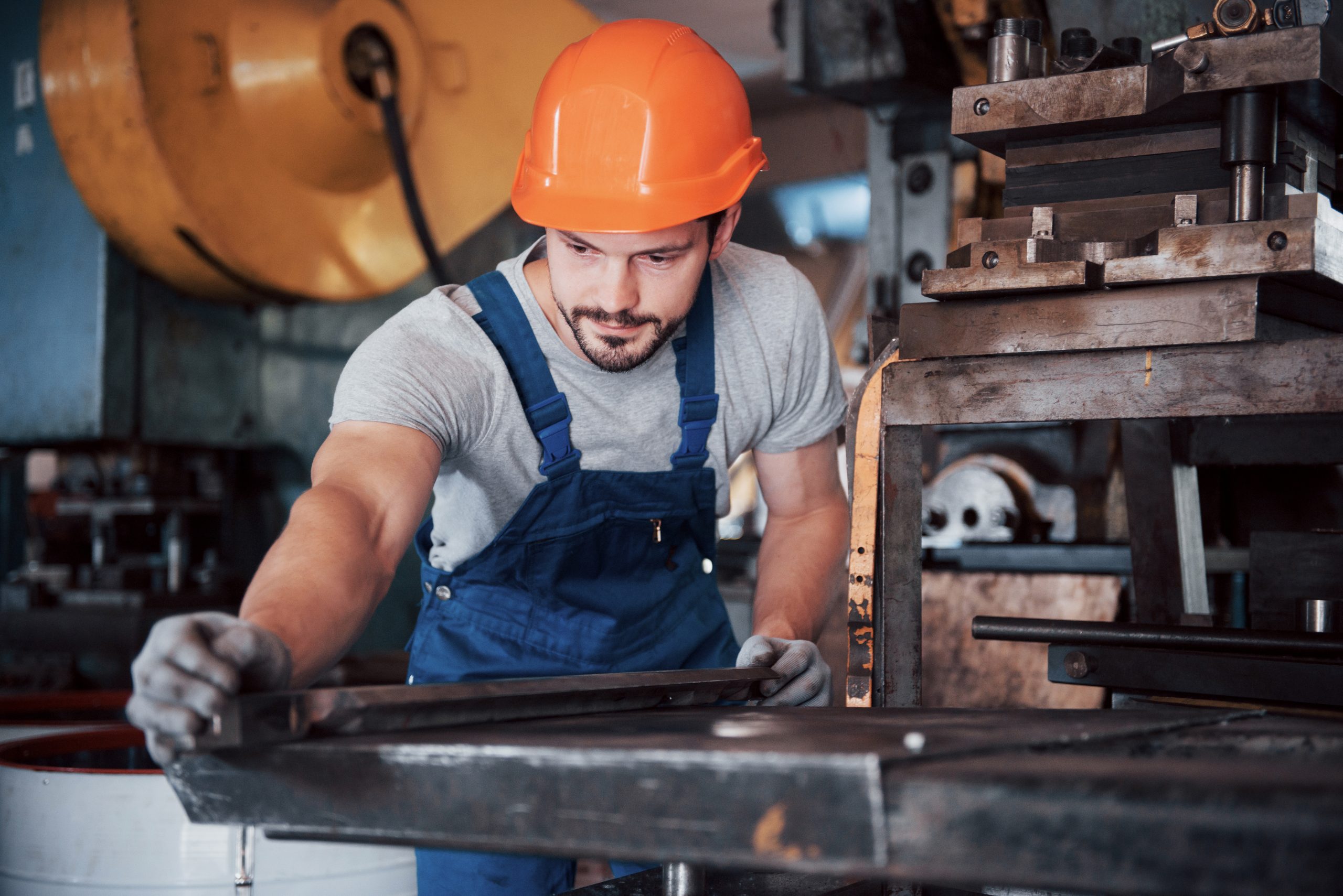 Portrait of a young worker in a hard hat at a large waste recycling factory. The engineer monitors the work of machines and other equipment.